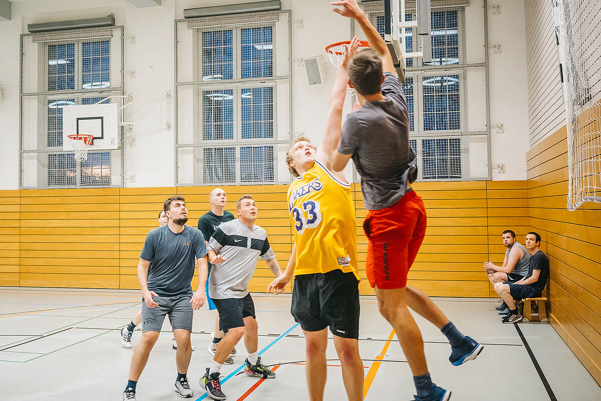 Basketball im Hochschulsport Eine Personengruppe spielt Basketball in der Sporthalle.